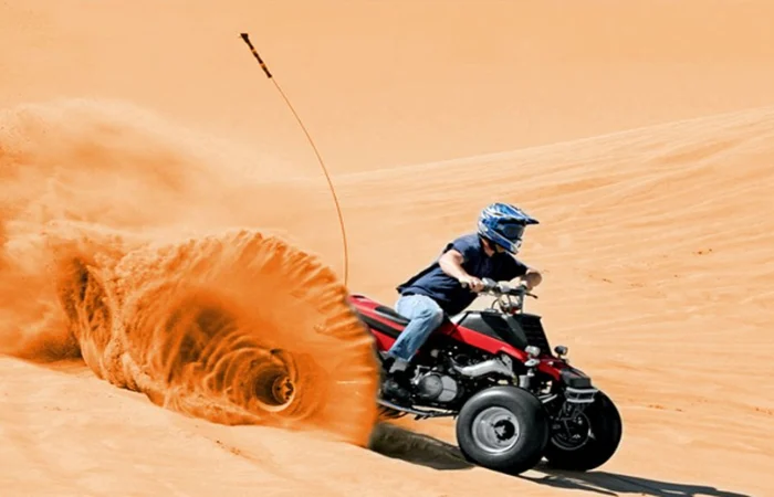 Dubai Desert Safari with Quad Bike – ATV rider powering over red sand dunes