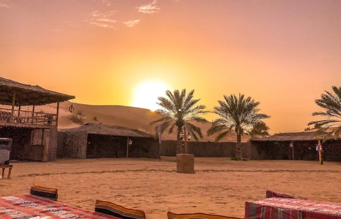 Evening Desert Safari Dubai – breathtaking golden sunset over red sand dunes with Bedouin camp in background